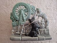 Front view of McCoy Spinning Wheel planter showing spinning wheel scene, dog, cat, base details