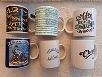 All six novelty coffee mugs arranged in two rows, fronts visible
