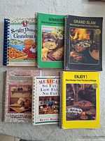 All six spiral-bound cookbooks laid out cover-up showing titles