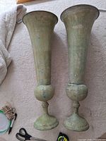 Pair of tall metal floor vases showing design and finish