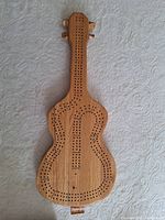 Full view of wooden guitar-shaped cribbage board without pegs inserted