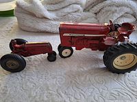 Large International Harvester model tractor and smaller red tractor side by side