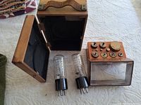 Overall view of open wooden weight box, separate weight block, two vacuum tubes
