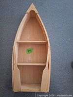 Front view of unfinished wood boat-shaped shelf showing three shelves and overall form