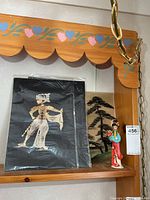 Full lot showing two artworks, additional artwork behind, and small doll