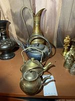 Group shot showing three kettles and tall brass vase