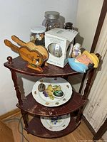 Full view of shelf showing all items: jars of buttons, ornament box, guitar stand, figurine, boat dish, plates and marbles