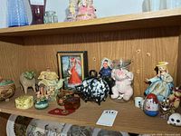 Overall view of shelf with collectibles, banks, trinket boxes, teapot and figurines