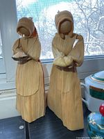 two corn husk figures in front of window