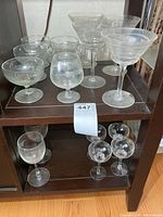 Assorted stemware on shelving, shows dessert dishes, margarita glasses, conical coupes, wine and cordial glasses