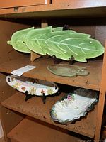 Green ceramic leaf platters and other dishes on shelf