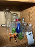 Shelf view showing entire assortment of glass bottles, jars and both small horse figurines