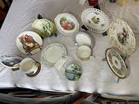 Group shot of all plates, cups, saucers and stands on table