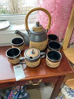 complete tea set arranged on table showing teapot, five cups and sugar bowl