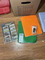 Overview of green binder, orange folder and bag of cards on floor
