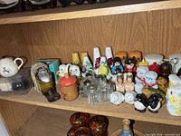 Overall view of middle and lower shelf showing majority of salt & pepper shakers and mini teapot