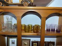 Shelf showing clear, amber and purple shot glasses grouped
