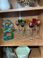 Shelf showing swan figurine and ten coloured tall stem glasses