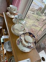 Assorted stacked teacups and saucers on shelf