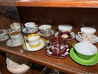 Front row of china and glass teacup sets on shelf