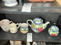 Full set on shelf showing teapot, creamer, sugar bowl, two mugs