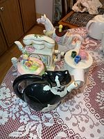 Group of five novelty ceramic teapots on lace tablecloth