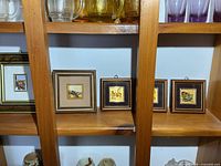 Five framed miniature pictures on shelf