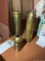 Three brass coffee grinder components displayed on tabletop
