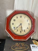 Front view of red octagonal Gilbert wall clock on box