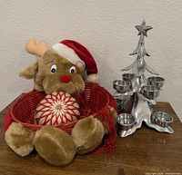 Overall lot showing aluminum Christmas tree candelabra, plush reindeer, red woven basket, ornament ball