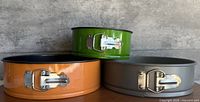 Three springform pans stacked, showing exterior colors and latches