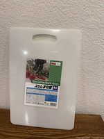 Front view of white slim cutting board showing carry handle and original label