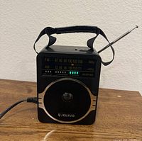 Front view of JEUJUG portable radio showing speaker, digital display, antenna, and power cord