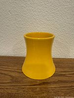 Front view of yellow hourglass ceramic vase on wooden surface