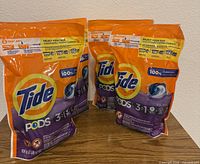 Three sealed Tide Pods 3-in-1 pouches standing on a table