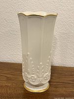 Front view of ivory porcelain vase with gold trim and embossed design
