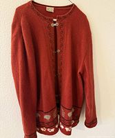 Full view of red wool cardigan hung on wall