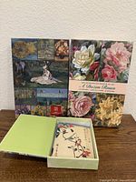 Two boxed notecard sets displayed; right box shows "A Dozen Roses" title, left collage cover; open box front shows Japanese design card
