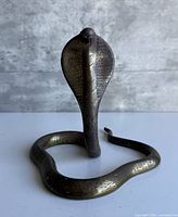 Front view of bronze cobra statue showing coiled body and hood