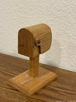 Front side of wooden mailbox-shaped stamp dispenser on base