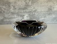 Side view of round crystal ashtray showing clear faceted exterior and purple interior