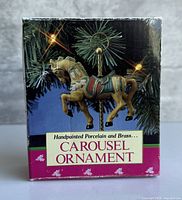 Front of boxed Carousel Ornament showing branding and artwork