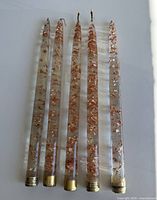 Five clear lucite candlesticks with copper flakes laid out full length