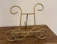 Front view of gold-tone metal scrollwork easel on tabletop