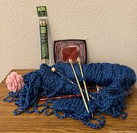 Lot overview showing blue yarn, loose bamboo needles, packaged Clover needles, red crochet hook, crochet swatches