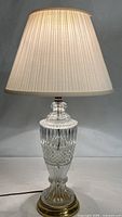 Full view of cut glass lamp with pleated shade illuminated