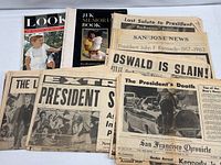 Stack of newspapers with assassination headlines and two magazines