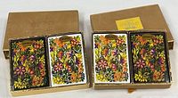 Two gold boxes each containing a pair of sealed floral Congress decks