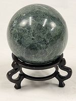 Full view of green stone sphere on stand