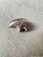 Front view of curved silver-tone bead showing patina and shape